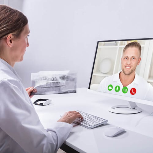 Doctor on a video-call with patient as she is holding x-rays in her left hand